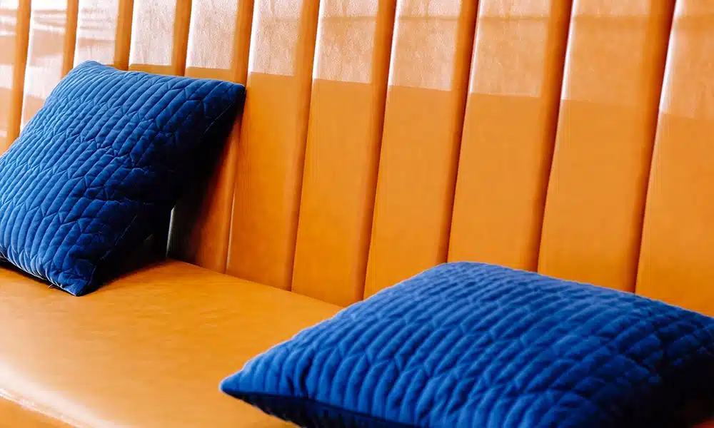 close up of an orange faux leather banquette seat in a deep fluted back style