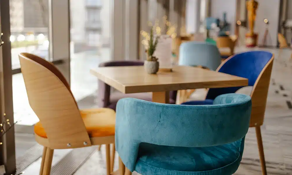 Close up of a group of restaurant chairs around a restaurant table, focused on the blue plush fabric
