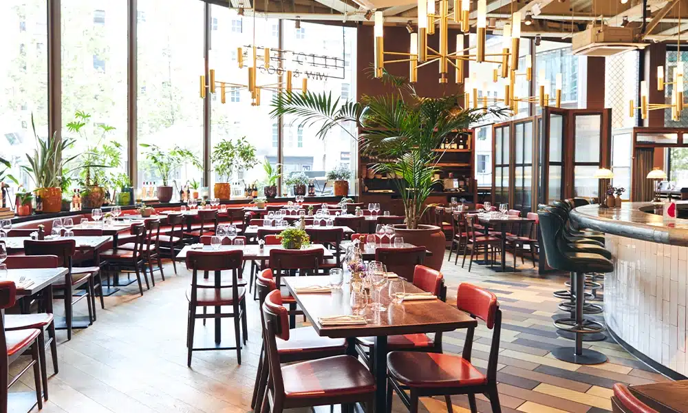 Large open plan restaurant with tables and chairs in the centre and booth seating around the outer perimeter