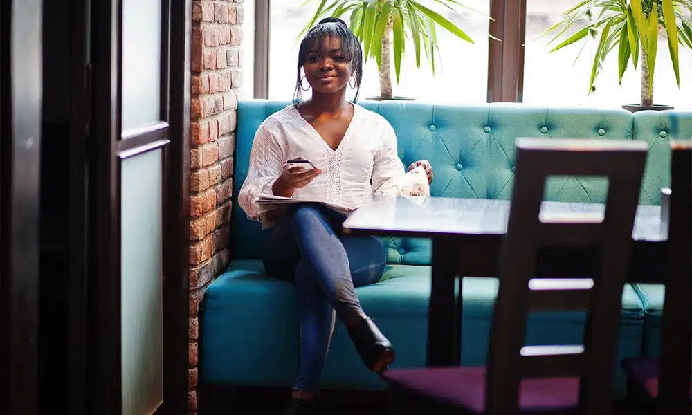 Woman sitting on blue button back booth seating in a restaurant interior