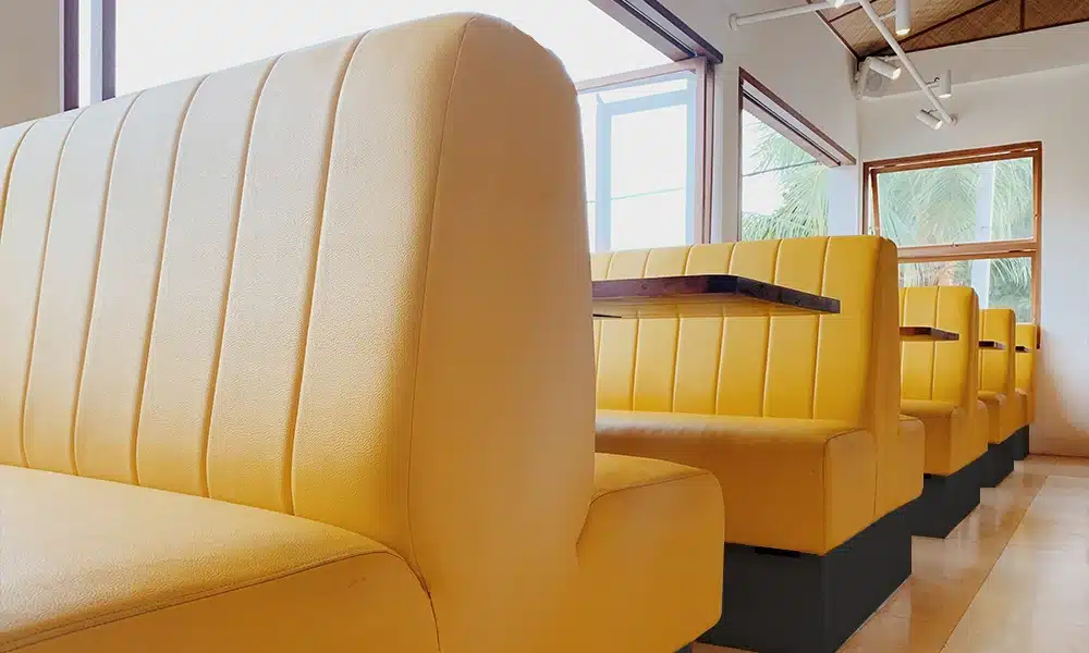 Yellow fluted back-to-back booth seating in a bright white café diner interior