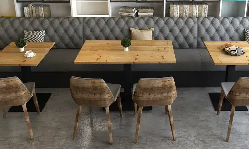 Cafe environment with chesterfield button back style booth seating up against a wall and tables infront