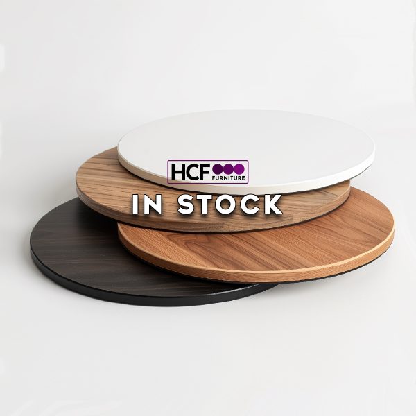 Round MFC laminate table tops stacked in different colours
