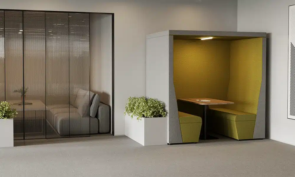 A qube acoustic meeting pod in a large open plan office space, the meeting pod is lit with LED lighting inside