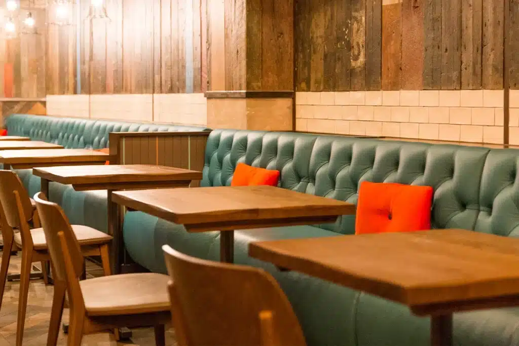 Continuous run of blue banquette seating with deep button-back upholstery along a restaurant wall.