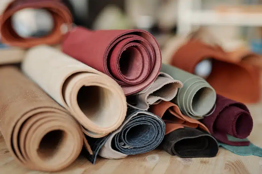 Faux leather upholstery fabric rolls stored on a shelf in a contract furniture workshop.