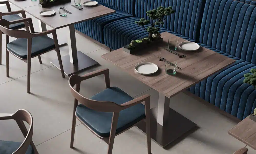 Beautifully decorated restaurant interior with walnut accents on table and chairs and fluted velvet blue booth seating