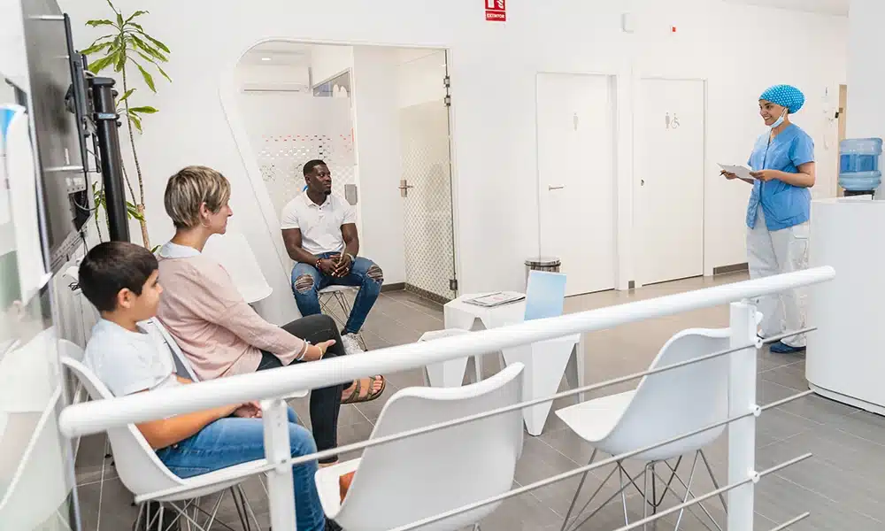 a GP waiting room with people sitting on commercial furniture inside