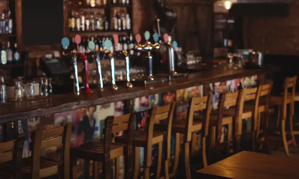 Rustic old style english pub bar with wooden bar stools surrounding