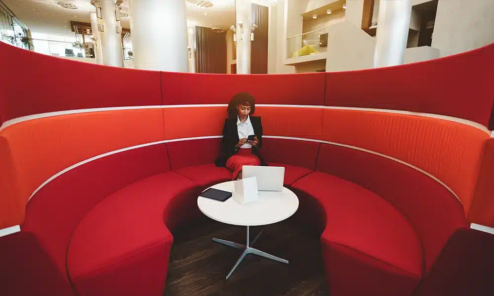 Large rounded meeting pod with high privacy backs in an office environment, office meeting pod in red