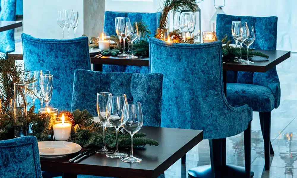 Luxurious blue suede dining chairs in a restaurant, black tables with tablewear on top