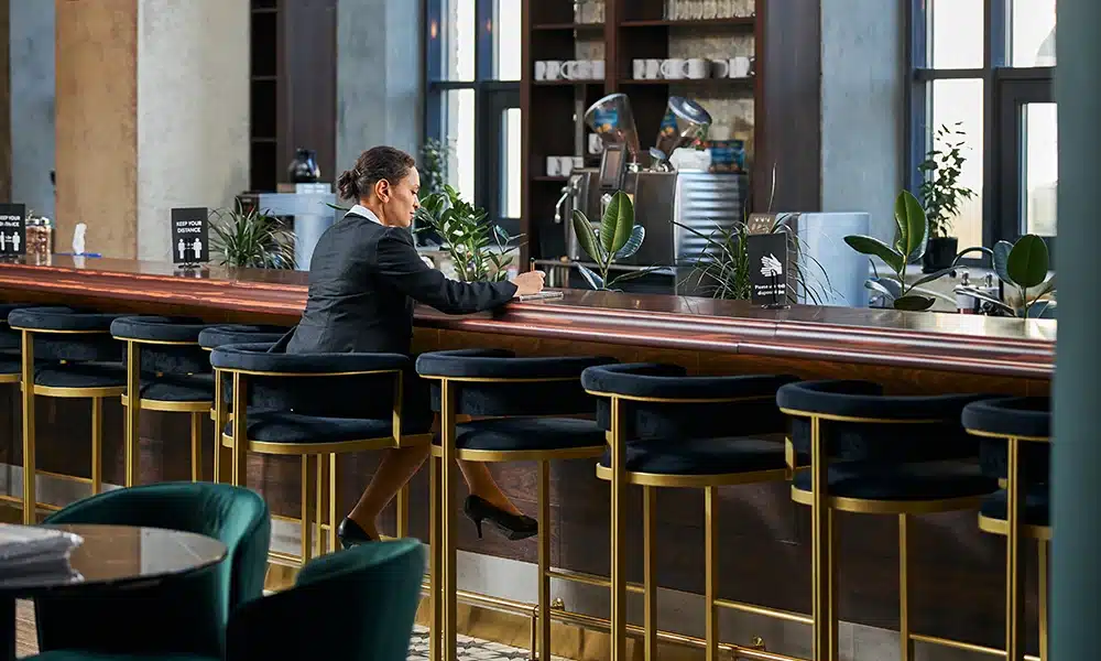 Gold and velvet bar stools next to a bar in a commercial hotel, business woman sits at the bar