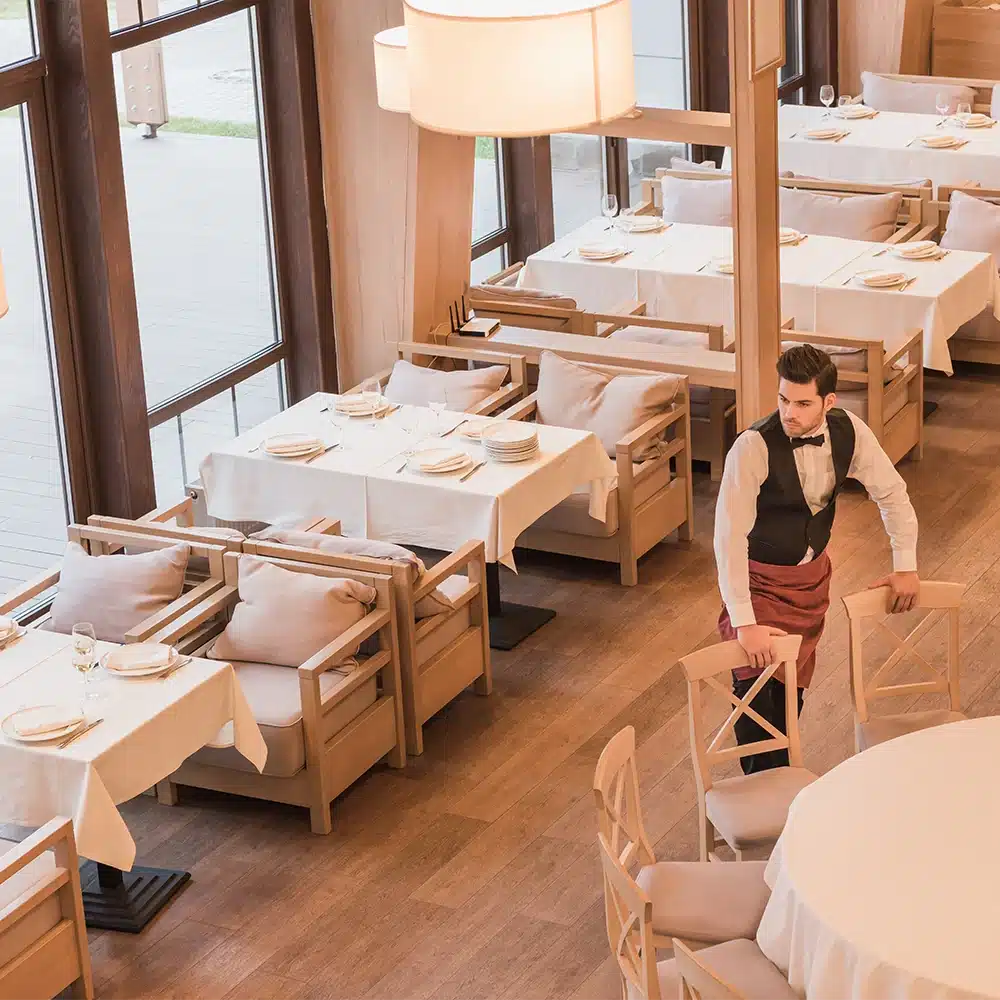 A waiter re-arranging furniture in a fancy luxury restaurant