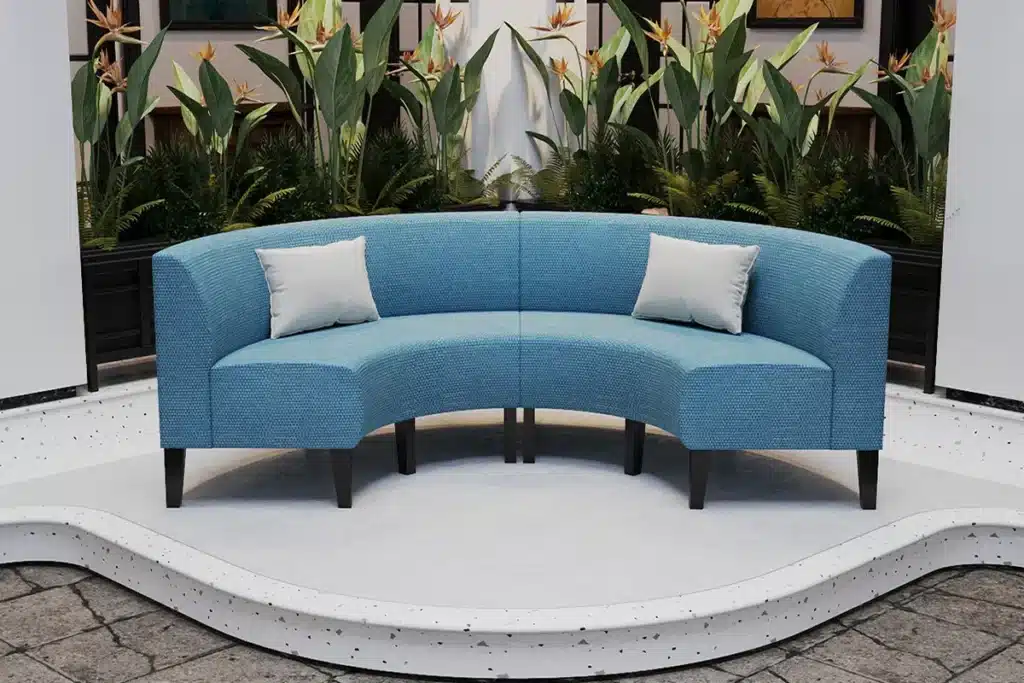 Outdoor half-round booth seating with blue upholstery and scatter cushions in a hotel or clubhouse courtyard.