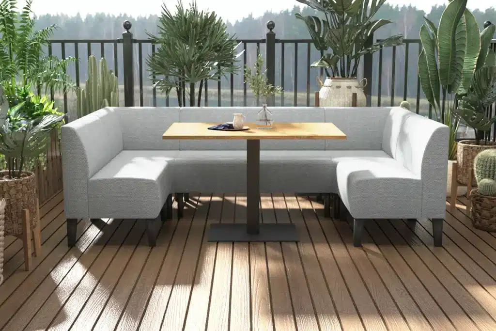 U-shaped outdoor booth seating on a balcony with plants surrounding and a contract laminate dining table in the centre.