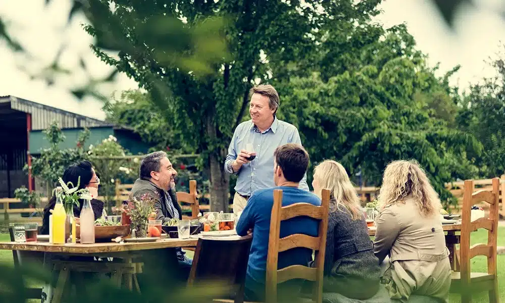 A pub garden with people sat around a wooden outdoor pub table on a sunny day