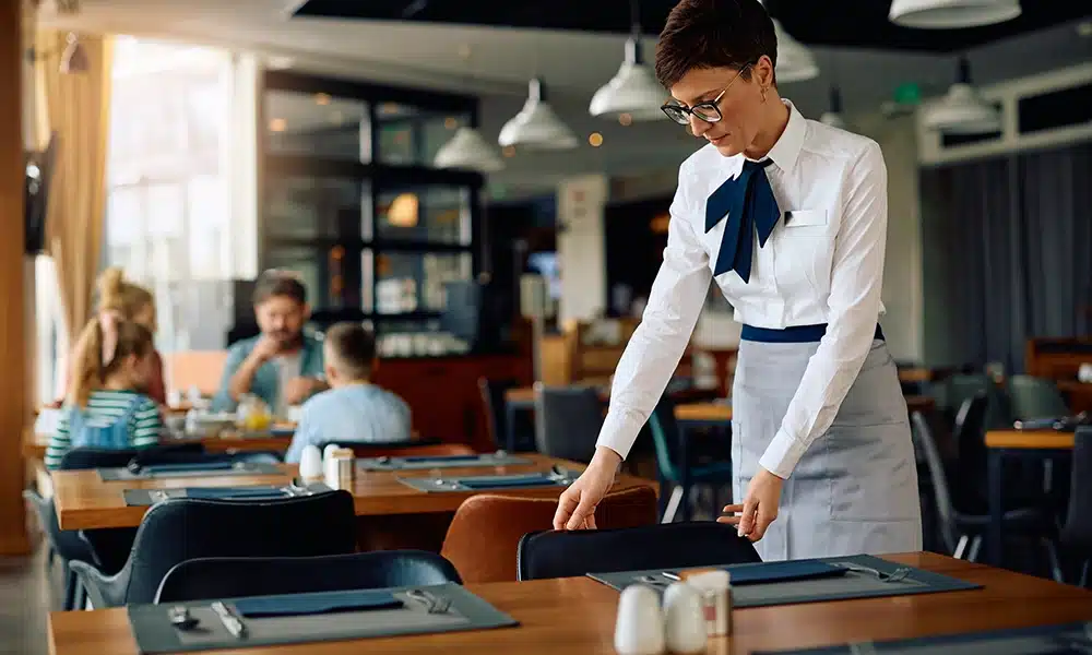 a waitier rearranging tables and chairs in a hotel restaurant
