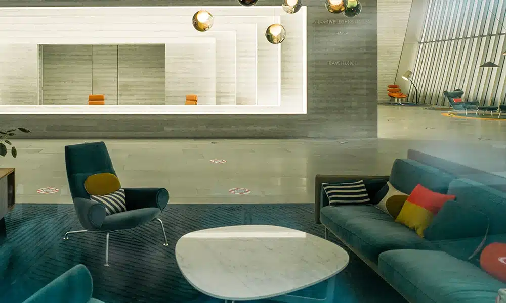 spacious interior of a hotel lobby with teal soft seating and sofas