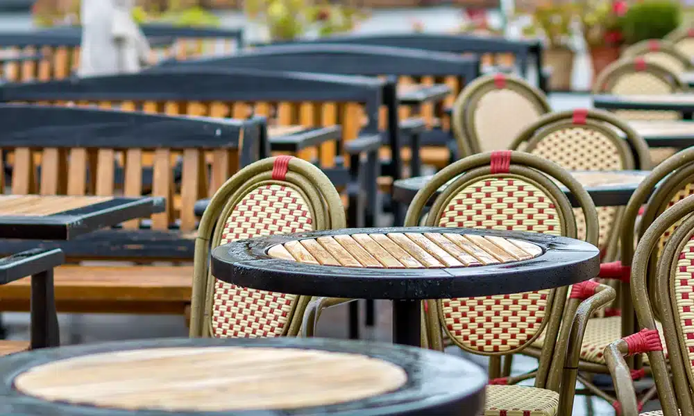 Outdoor commercial woven dining chairs, metal exterior tables in a rainy cafe terrace