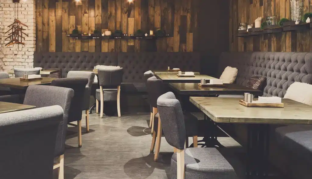 Banquette seating in a dimly lit restaurant interior, live oak wood walls and chairs around the room