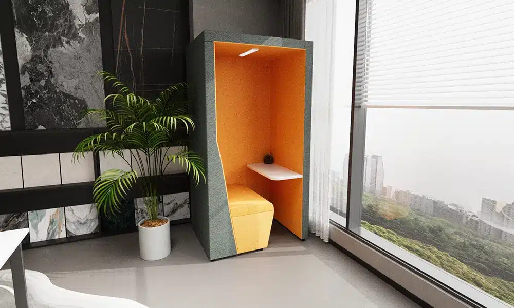 Solo Single seater acoustic pod in a bright office space, bold bright orange interior colour and white table is lit up by the interior lighting