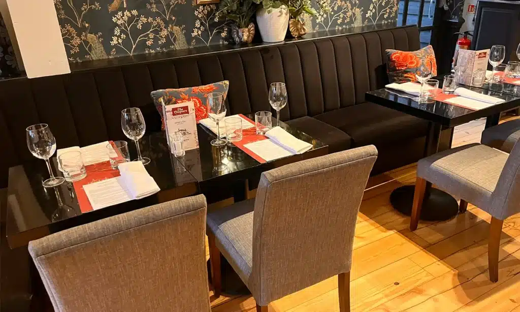 Deep fluted booths with tables and chairs opposite in a pub setting, tables made up for dining