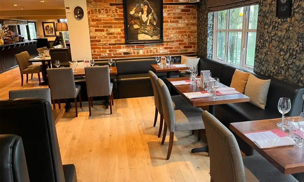 pub interior with solid wood tables and chairs, live brick walls and Plain back booths surround the room