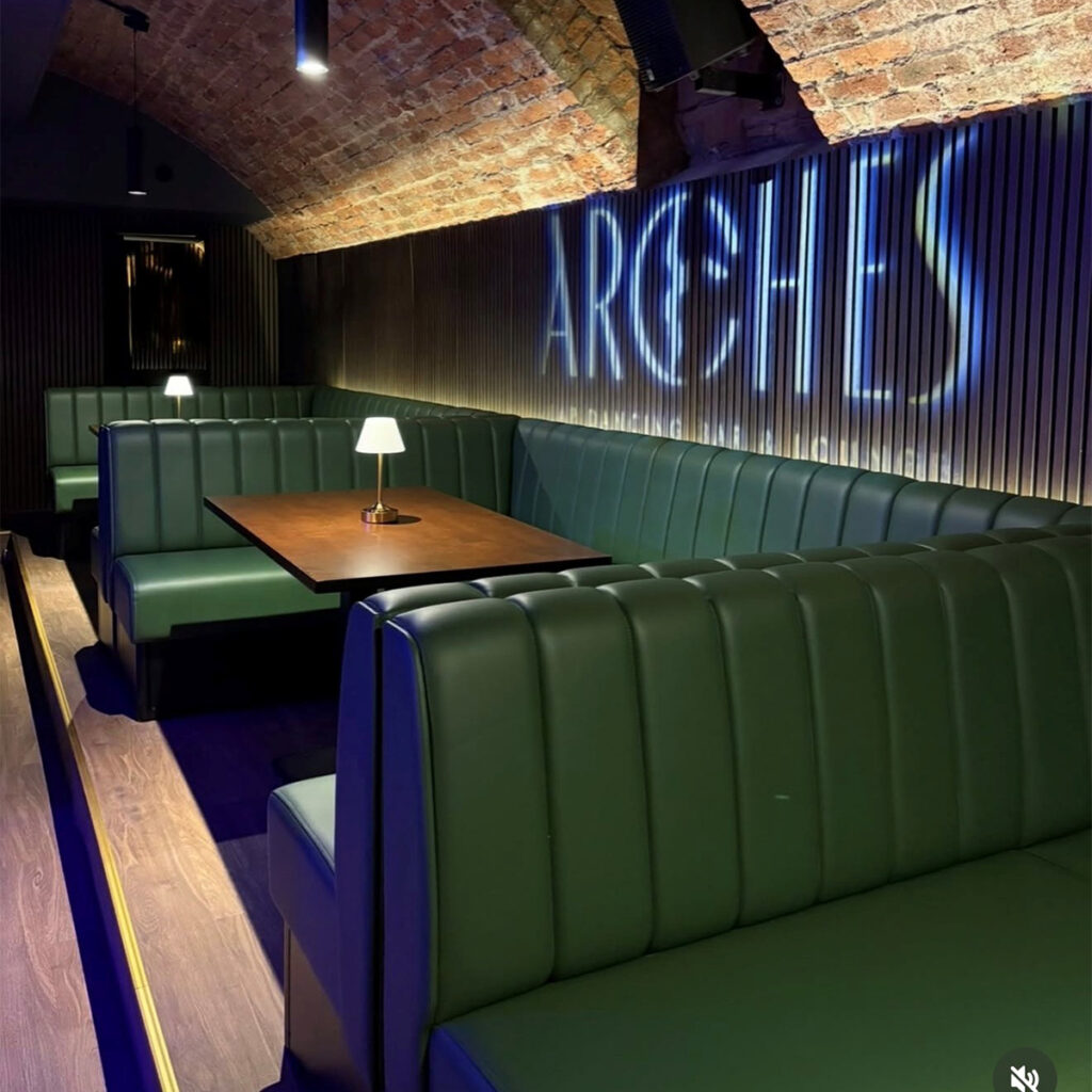 Illuminated deep fluted banquette seating beside living wall at Arch Bar